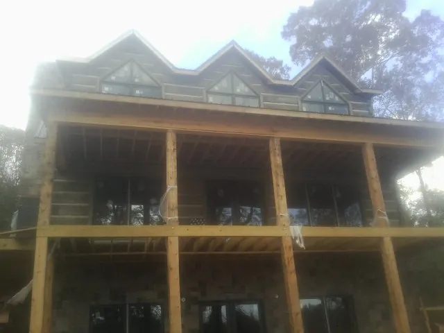 Dormers and porch framing on a large log home under construction — Roof Coating work by our crew in Swanton