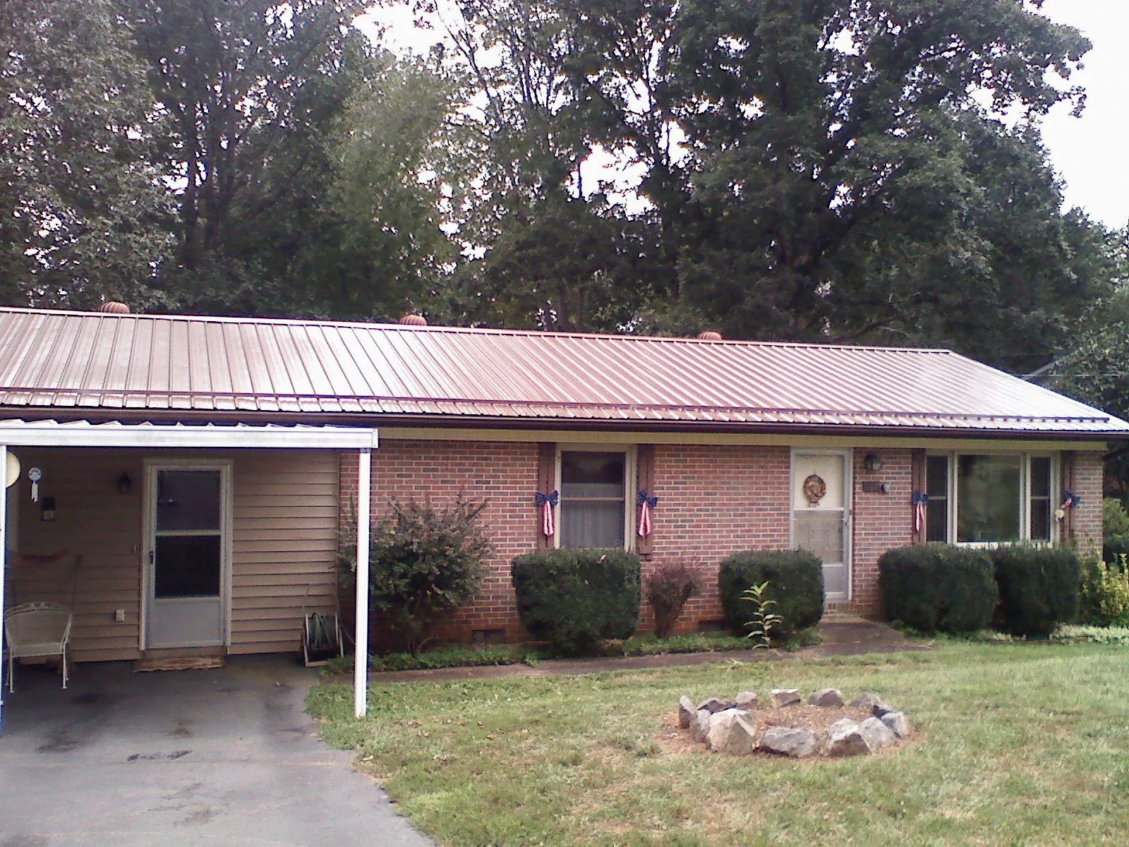 Bronze metal roof and carport on a brick ranch home — Roof Repair work by our crew in Swanton